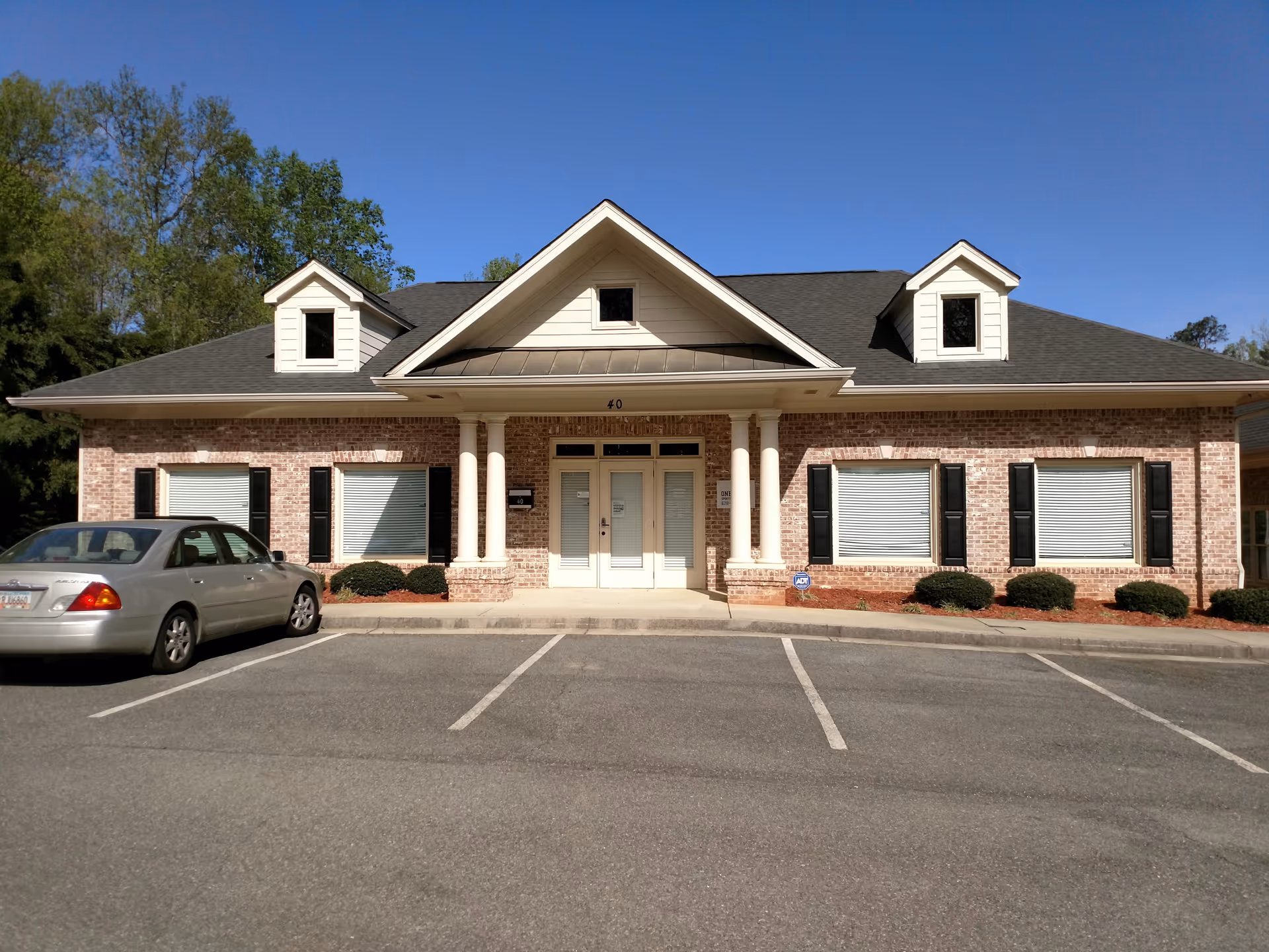 Brick senior living facility with white-columned entrance and front parking.