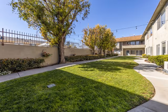 Outdoor courtyard at Brookdale Valley View with lawn, trees, and string lights.