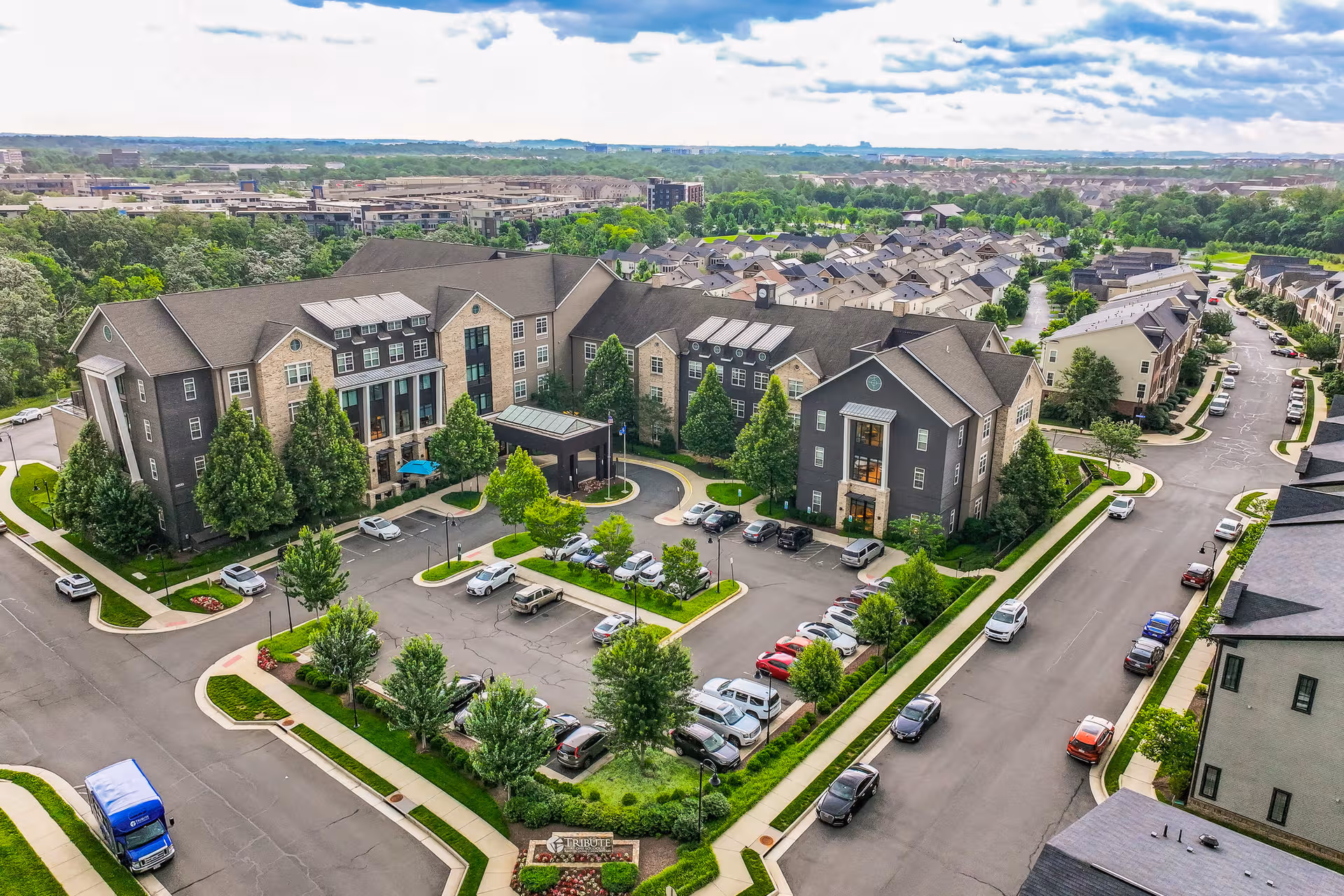 Aerial view of a multi-building senior living campus with parking and greenery.