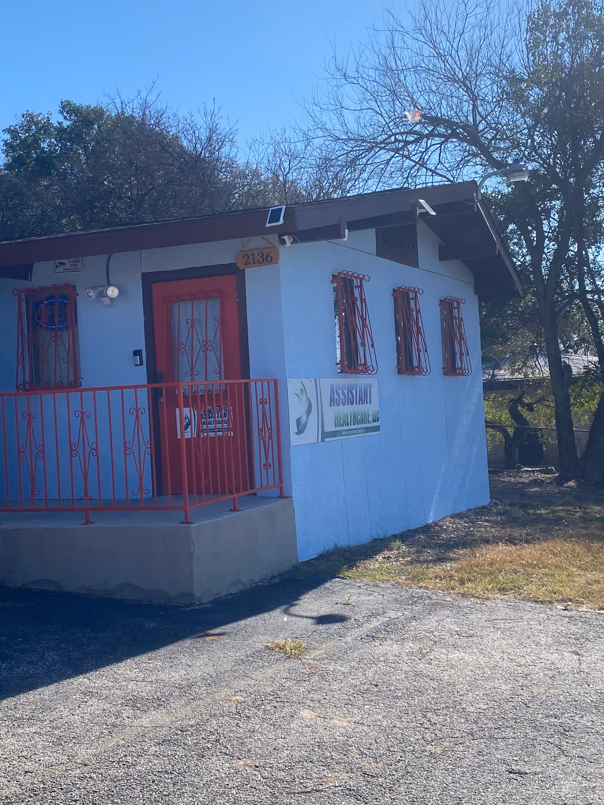 Small blue building with red door and railing, signage for Assistant Healthcare LLC.
