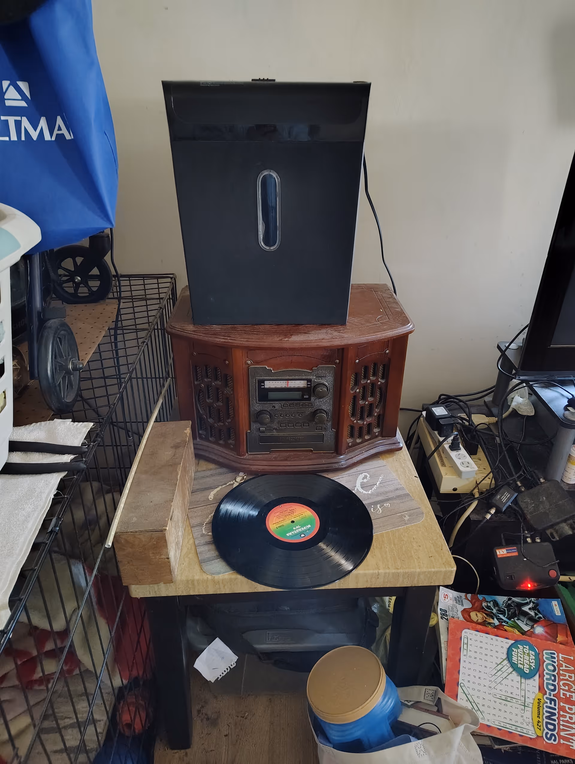 Cluttered corner with vintage wooden stereo cabinet, turntable, and a vinyl record.