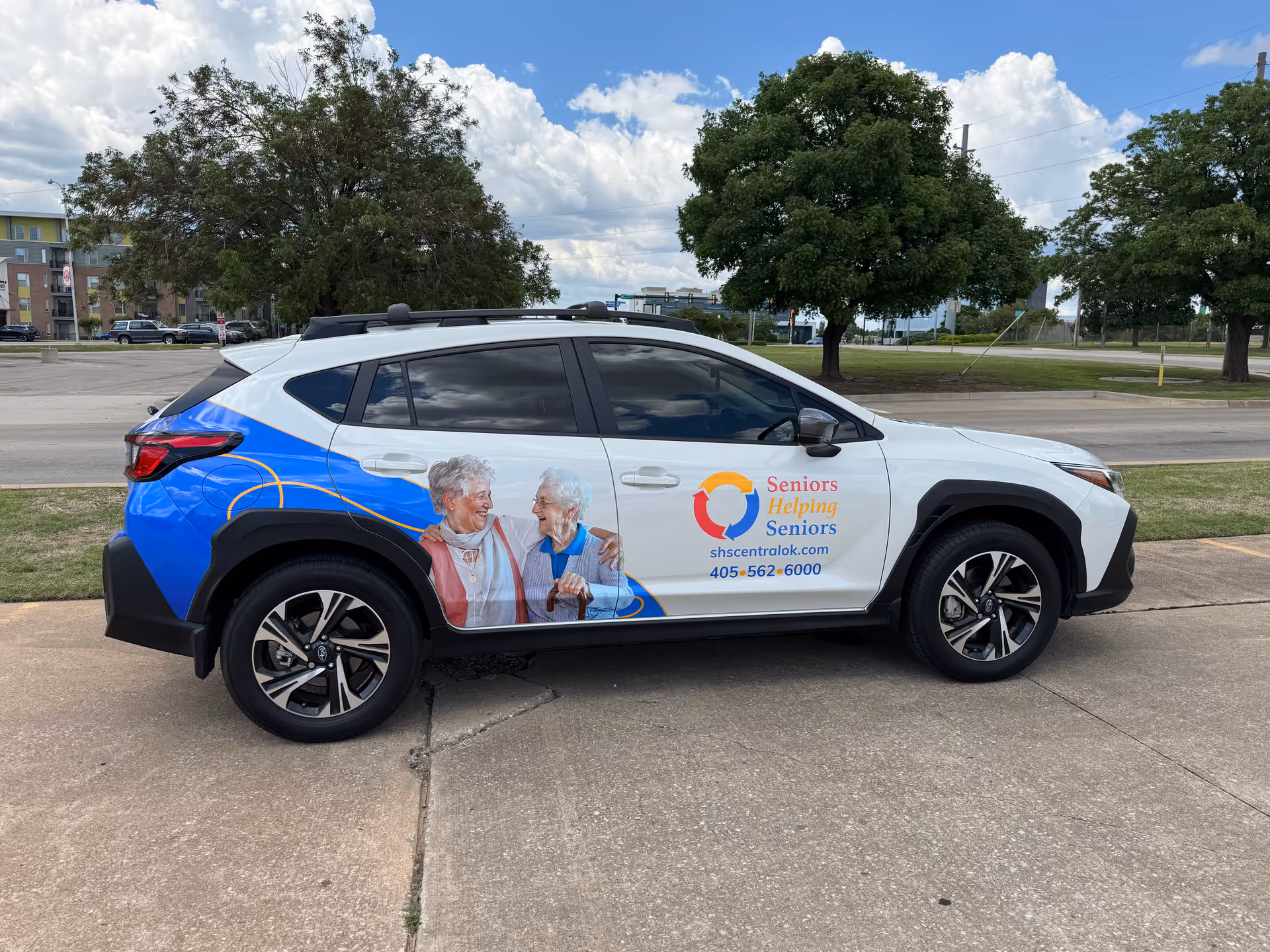 White promotional SUV parked on a street, featuring Seniors Helping Seniors Central Oklahoma branding.