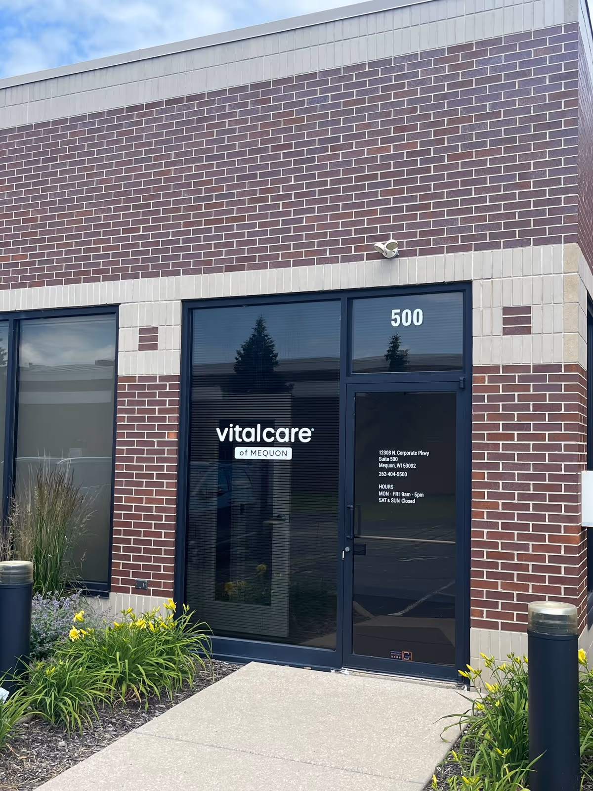 Brick exterior of Vital Care of Mequon with glass entry door and landscaping.