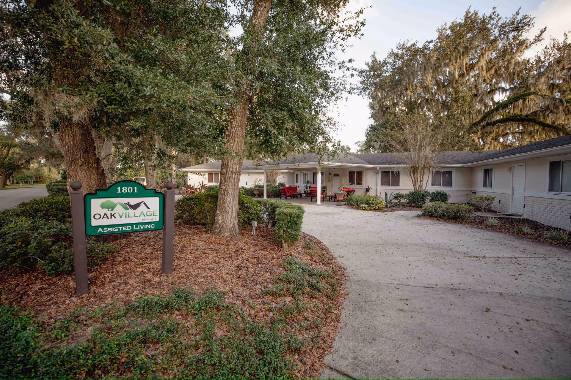 Exterior view of Oak Village assisted living with a driveway, sign, and single-story building entrance.