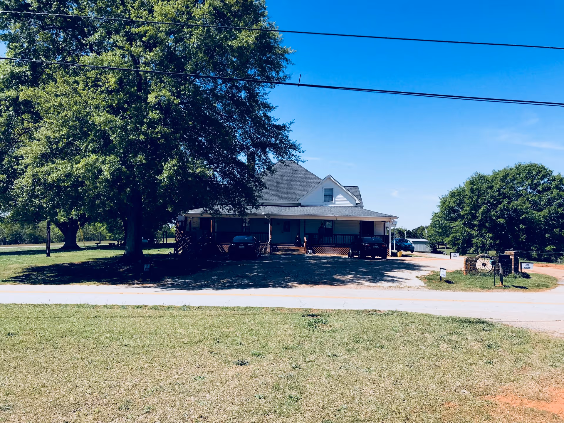 Exterior view of Oakridge Community Care Home with a front porch, cars, and tall trees.