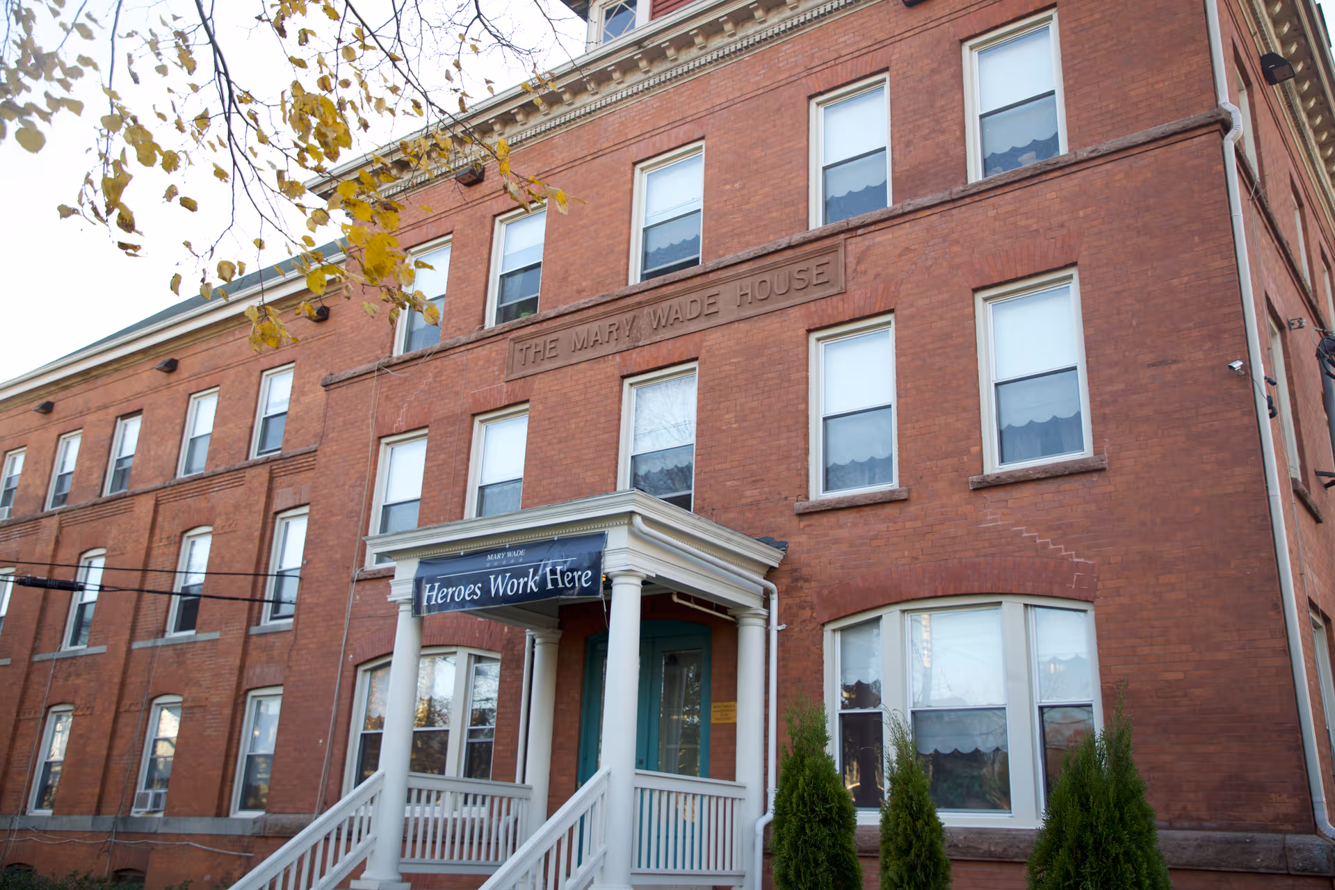 Brick building with a front entrance, sign reading 'Heroes Work Here', and white porch steps.