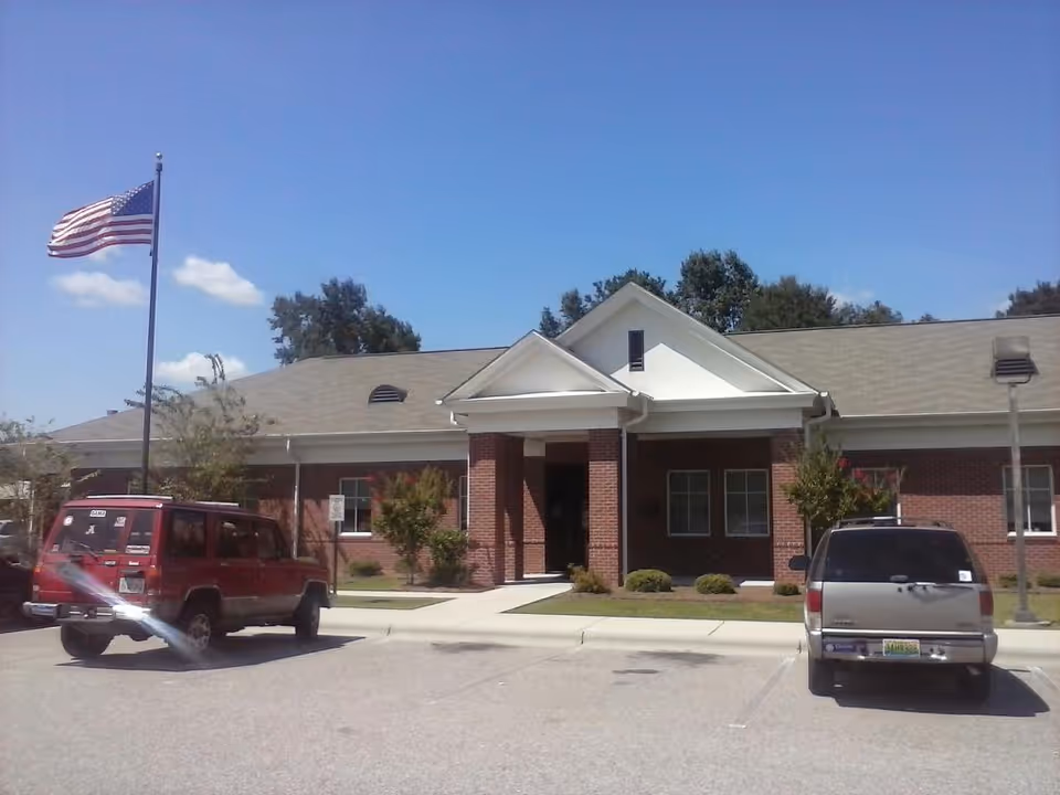 Front view of Dale County Health Department building with flagpole and parked vehicles.