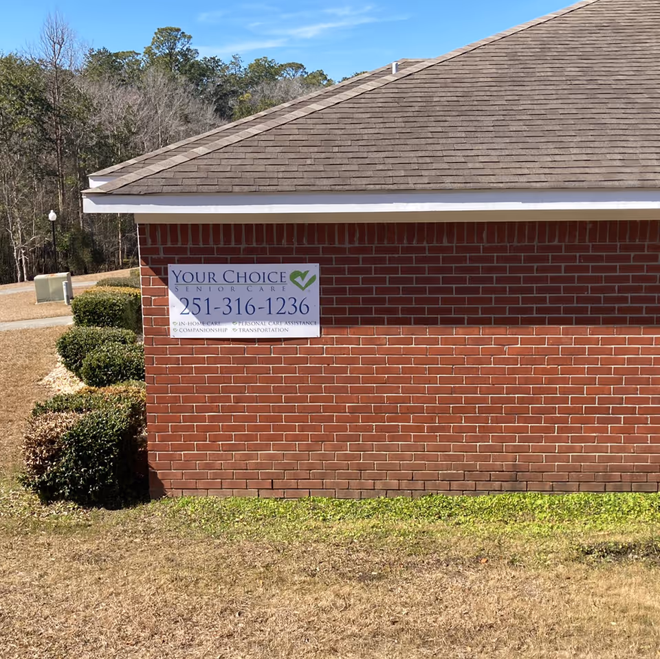 Brick exterior of Your Choice Senior Care facility with a sign on the wall and greenery.