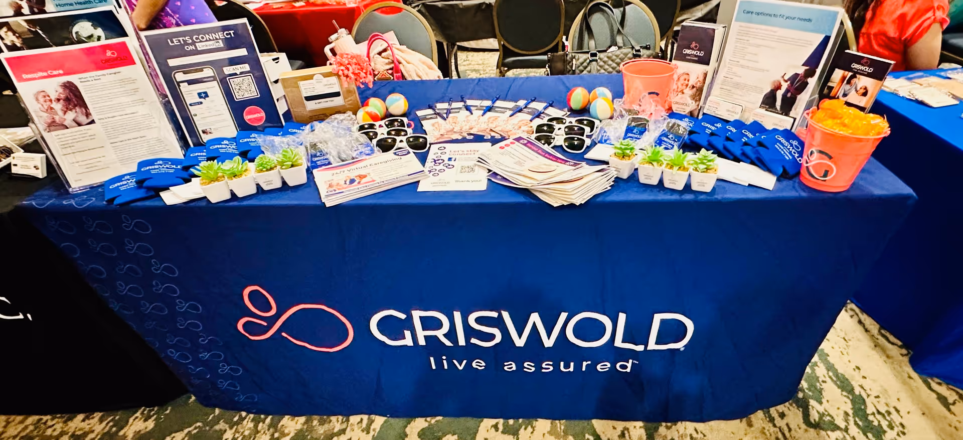 Promotional booth with Griswold branding, brochures, and giveaways on a blue table indoors.