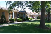 Row of single-story senior living units with manicured lawns and trees.