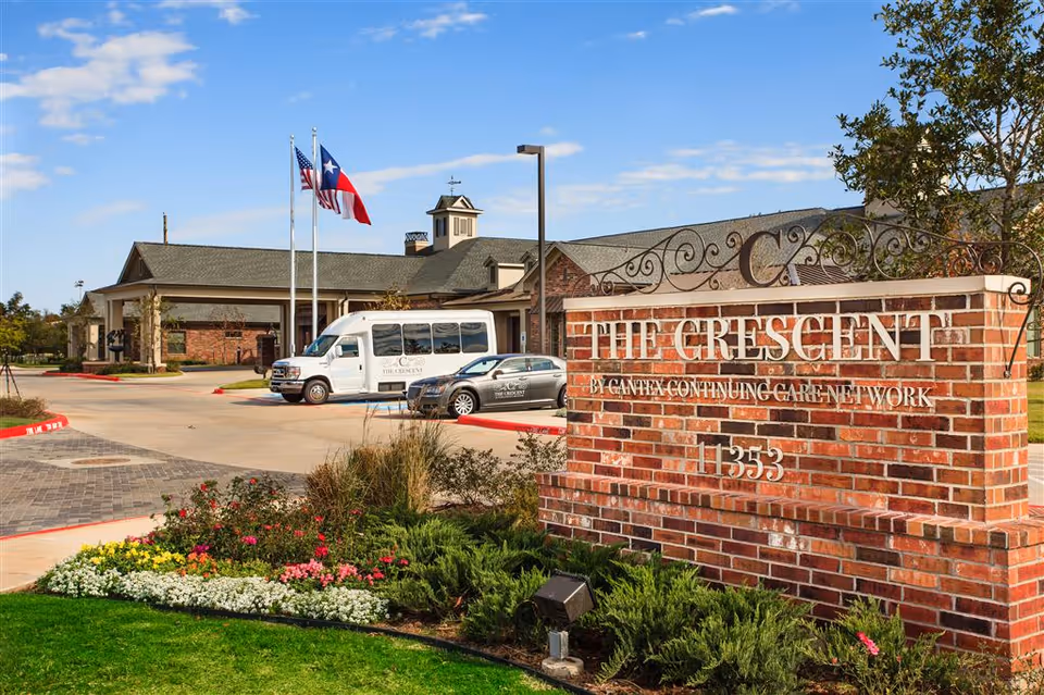 Brick sign reads The Crescent outside a single-story senior living facility.