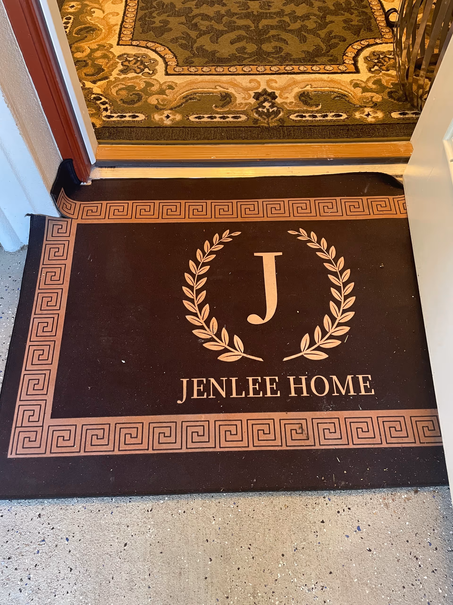Open doorway reveals a decorative floor mat with 'Jenlee Home' and a laurel emblem