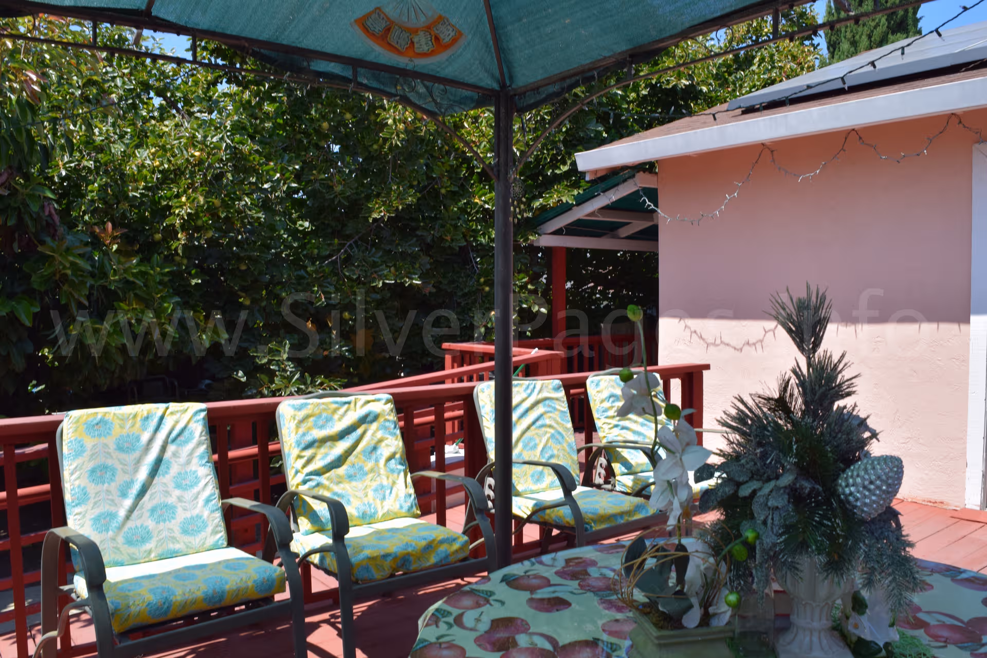 Outdoor patio with four cushioned chairs and a table on a pink building deck.