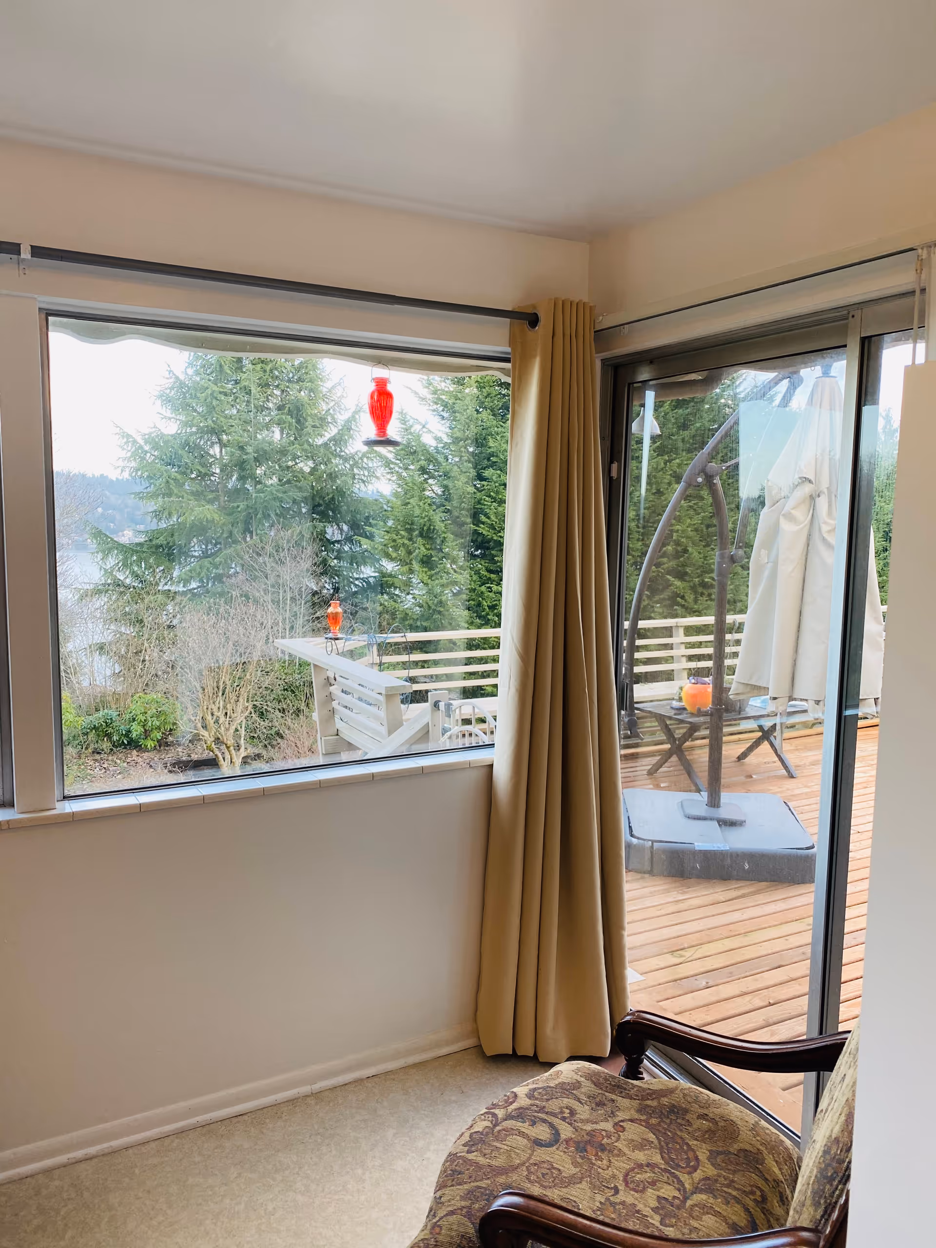 Interior living area with a sliding glass door to a wooden deck and beige curtains.