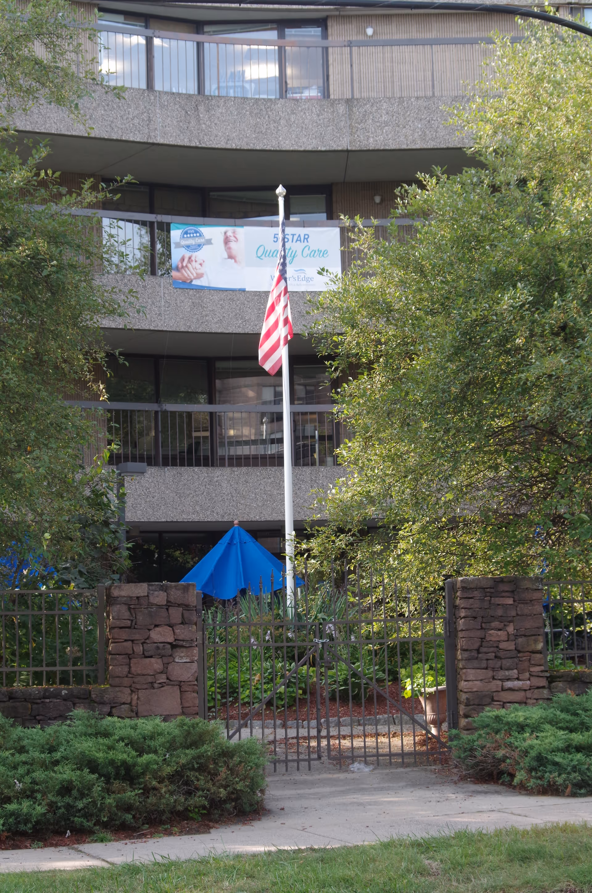 Front exterior of Water's Edge Center for Health and Rehabilitation with flagpole and banner.