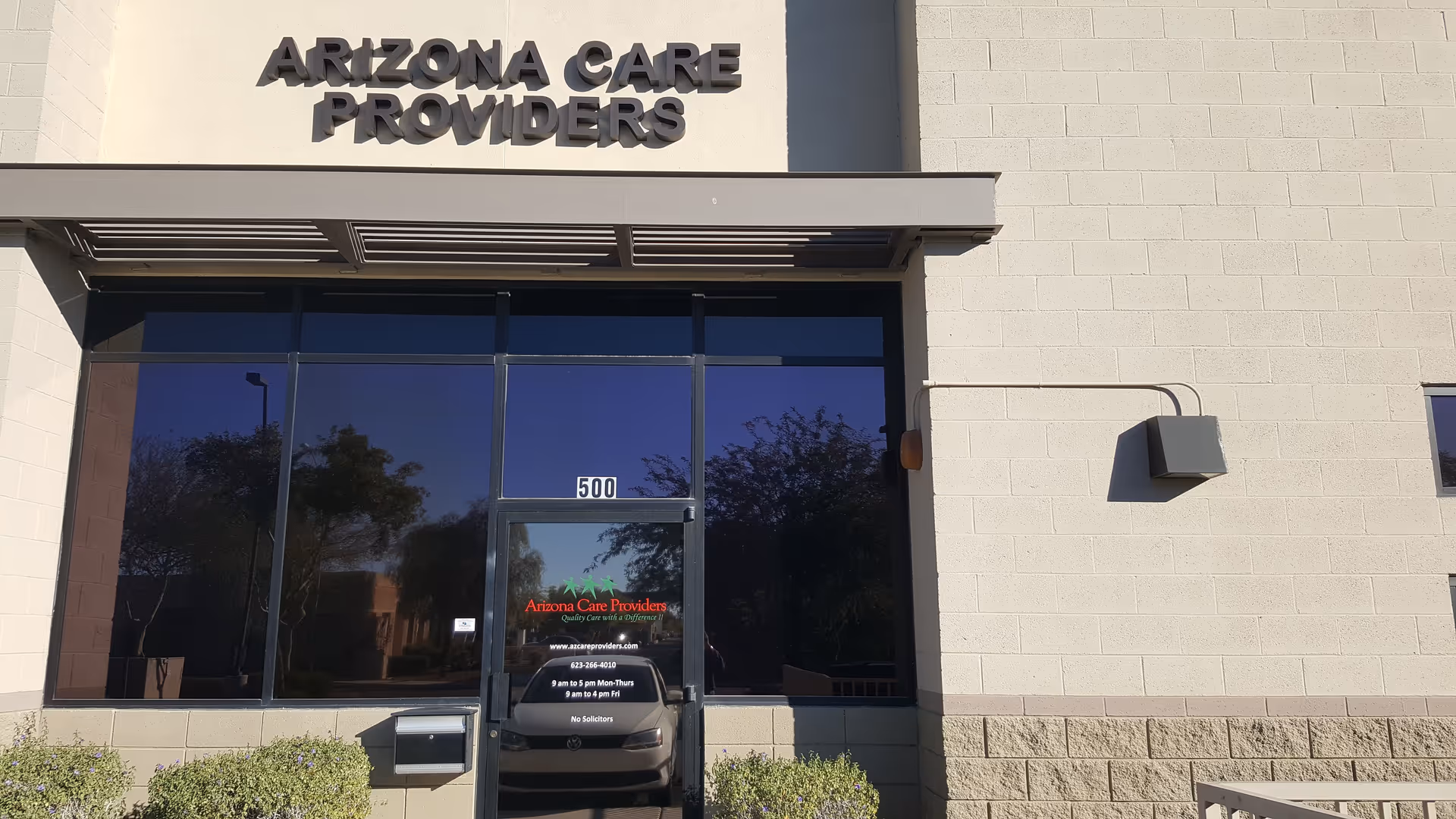 Front exterior of Arizona Care Providers facility with glass doors and signage.