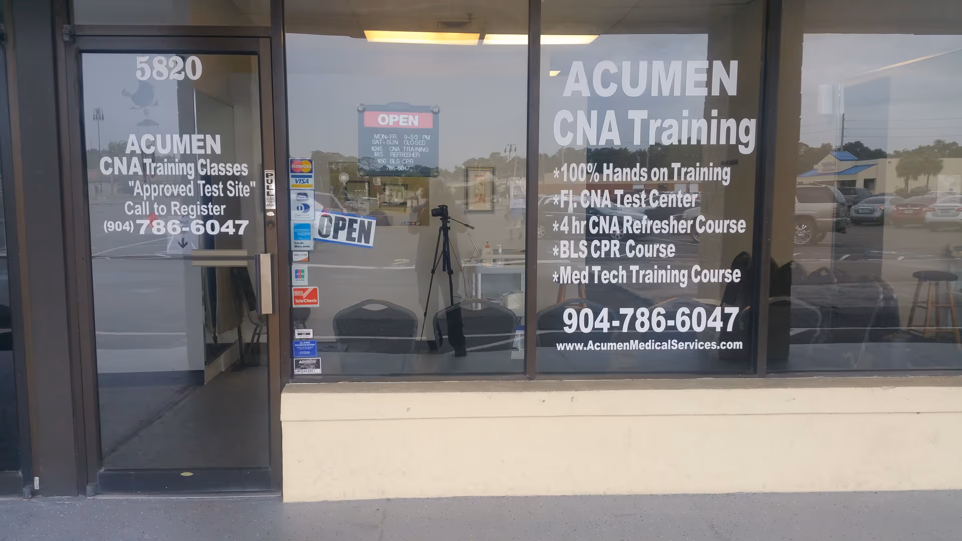 Glass storefront displaying Acumen CNA Training Center signs with an OPEN sign.