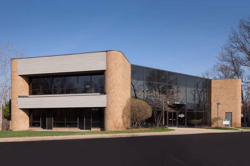 Two-story brick and glass building with a curved brick facade and glass entrance