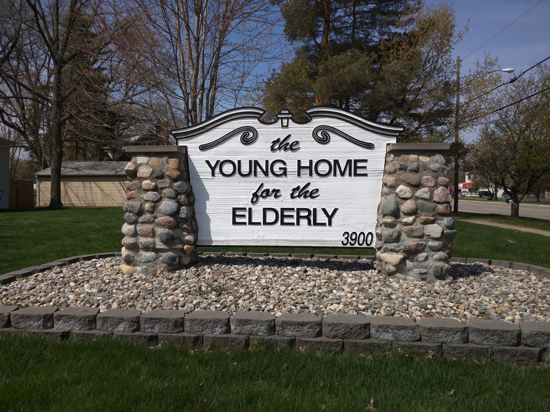 Outdoor stone sign reading 'The Young Home for the Elderly' in front of grass.