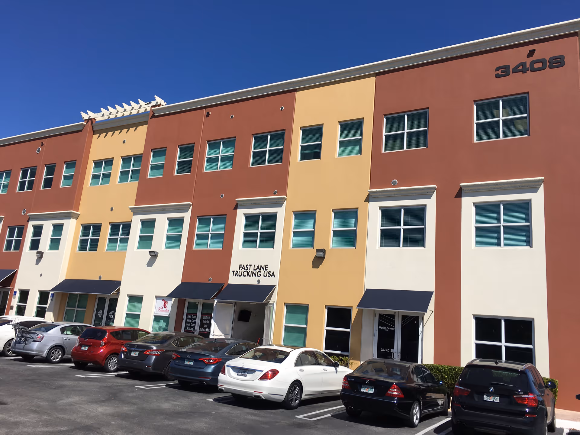 Colorful three-story building with windows and parked cars in front