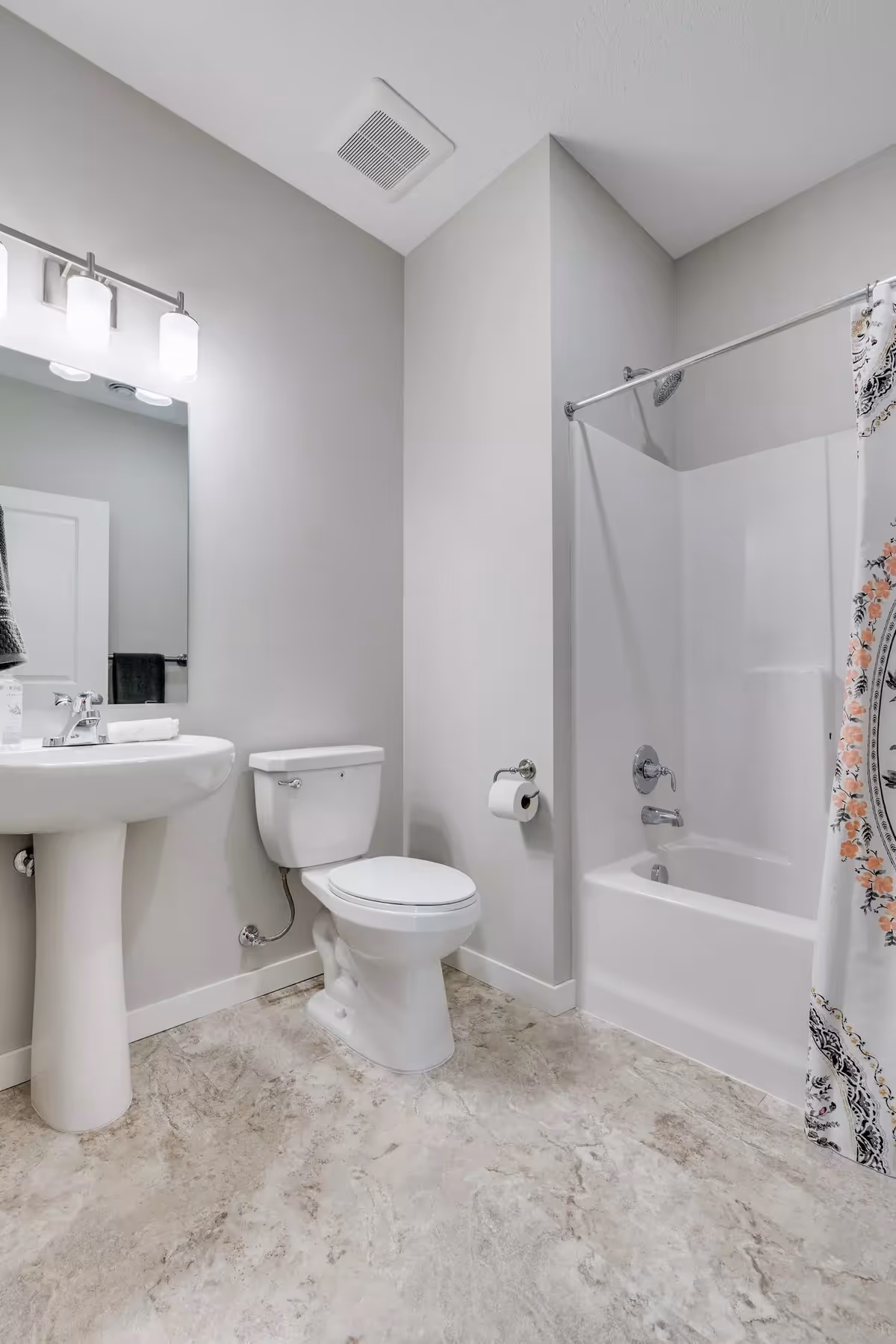 Bright, modern bathroom featuring a pedestal sink, toilet, and shower.