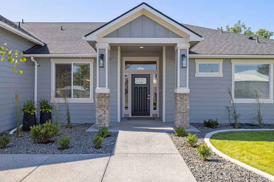 Gray ranch-style building exterior with a covered entry and landscaped walkway.