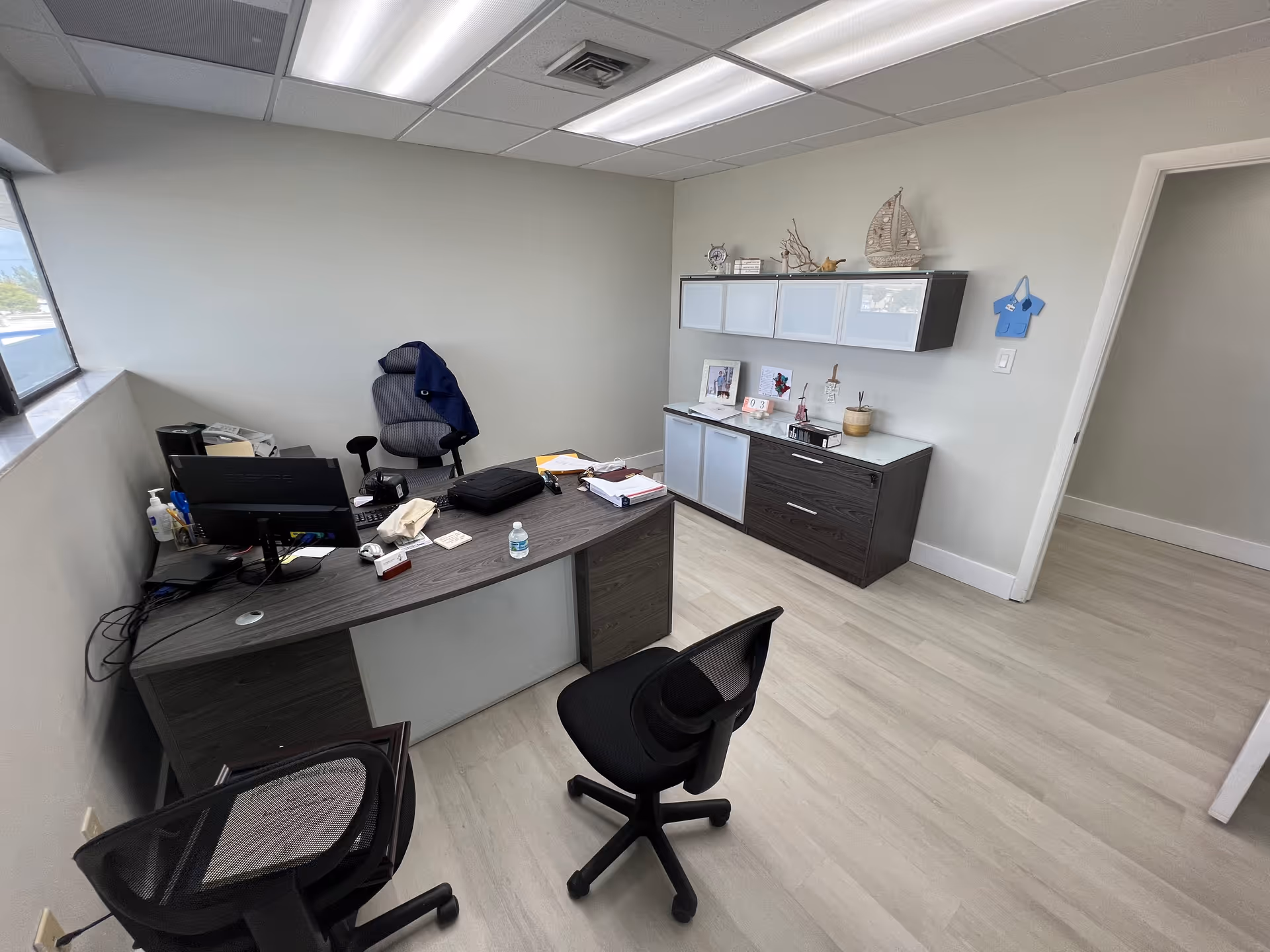 Office workspace inside Continuum Care of Miami featuring a desk, computer, chairs, and storage cabinets.