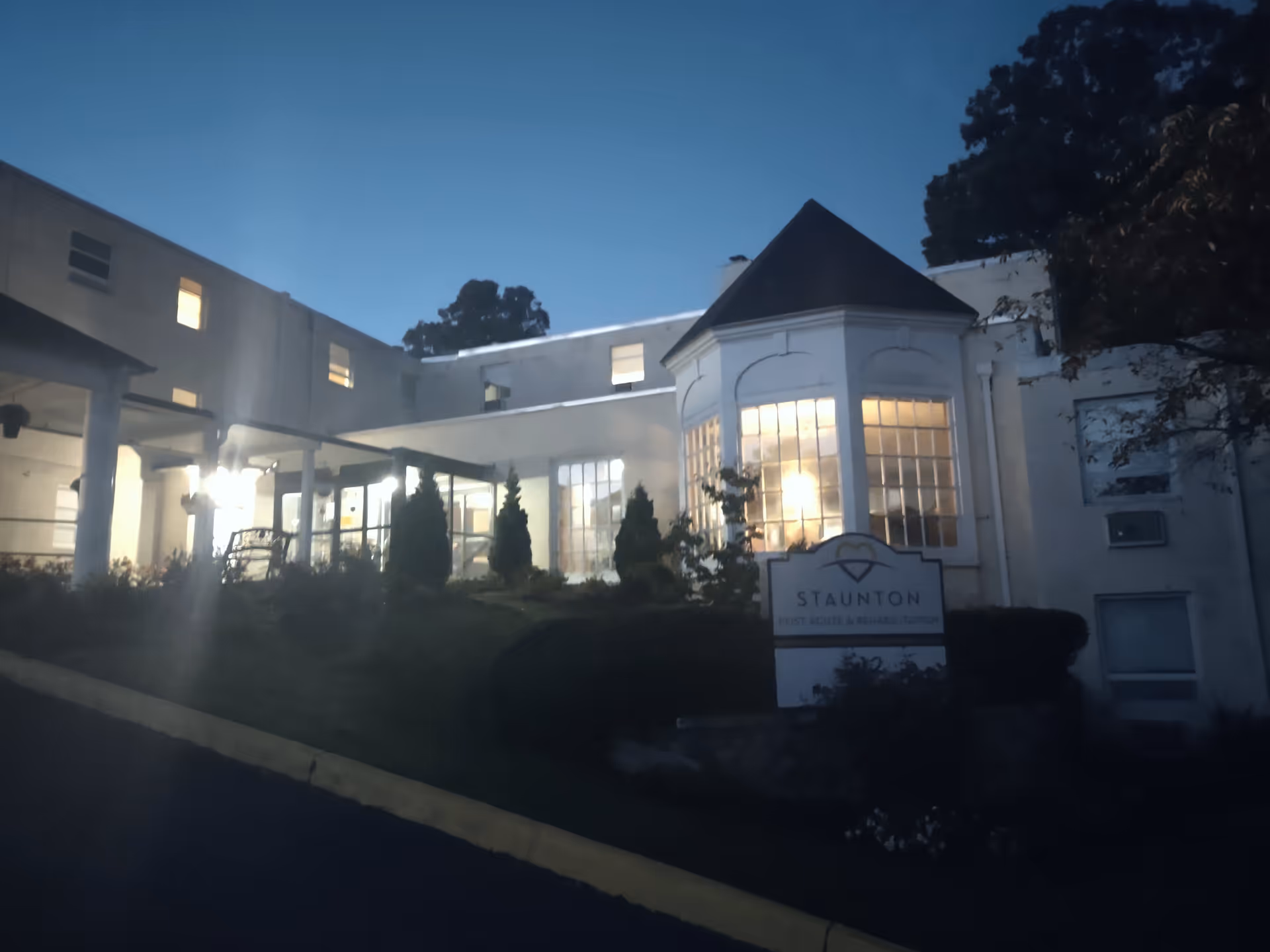 Twilight exterior of Envoy of Staunton facility with illuminated windows and front sign