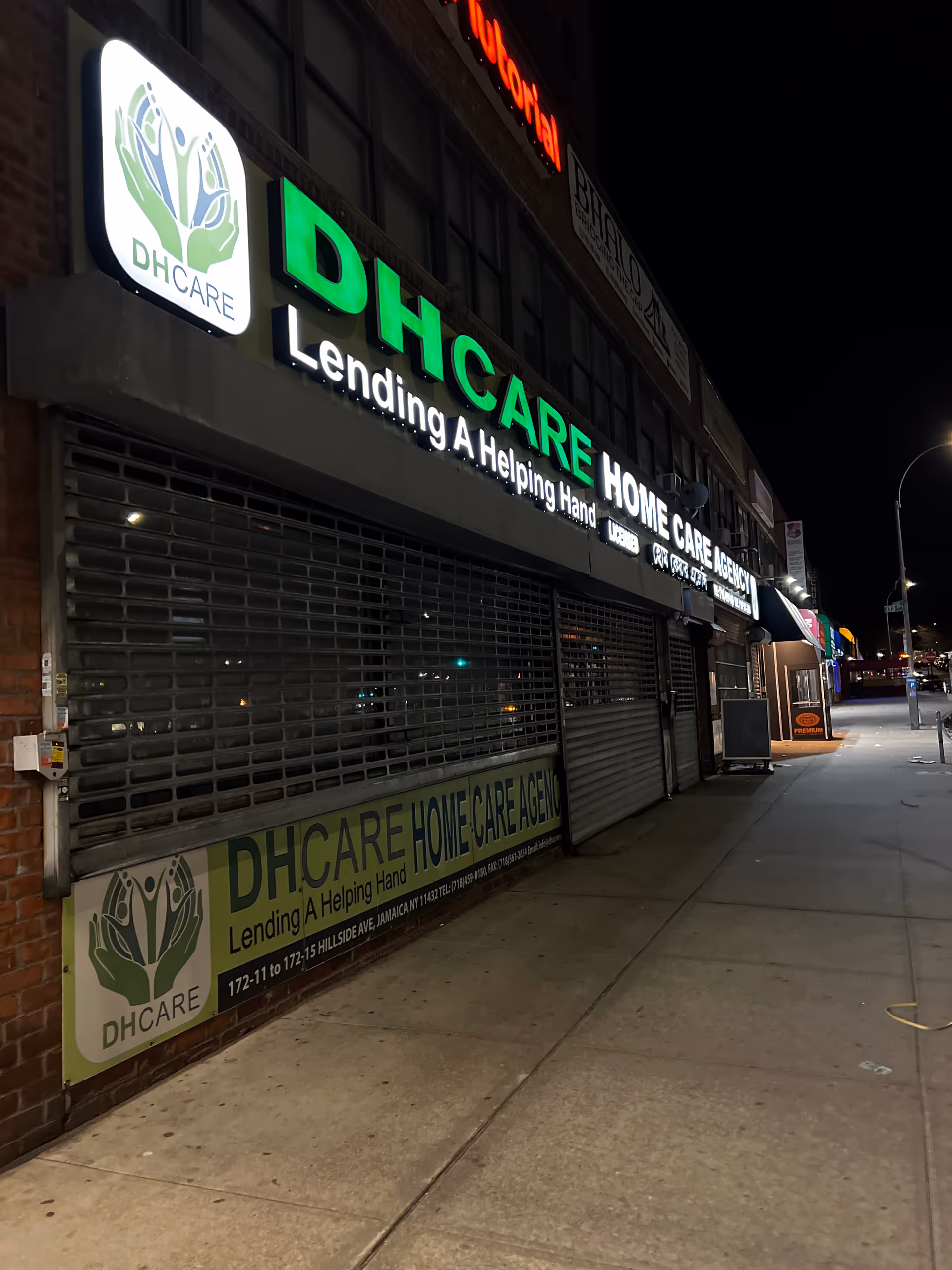 Nighttime exterior of a DHCARE Home Care Agency storefront with a bright green sign.