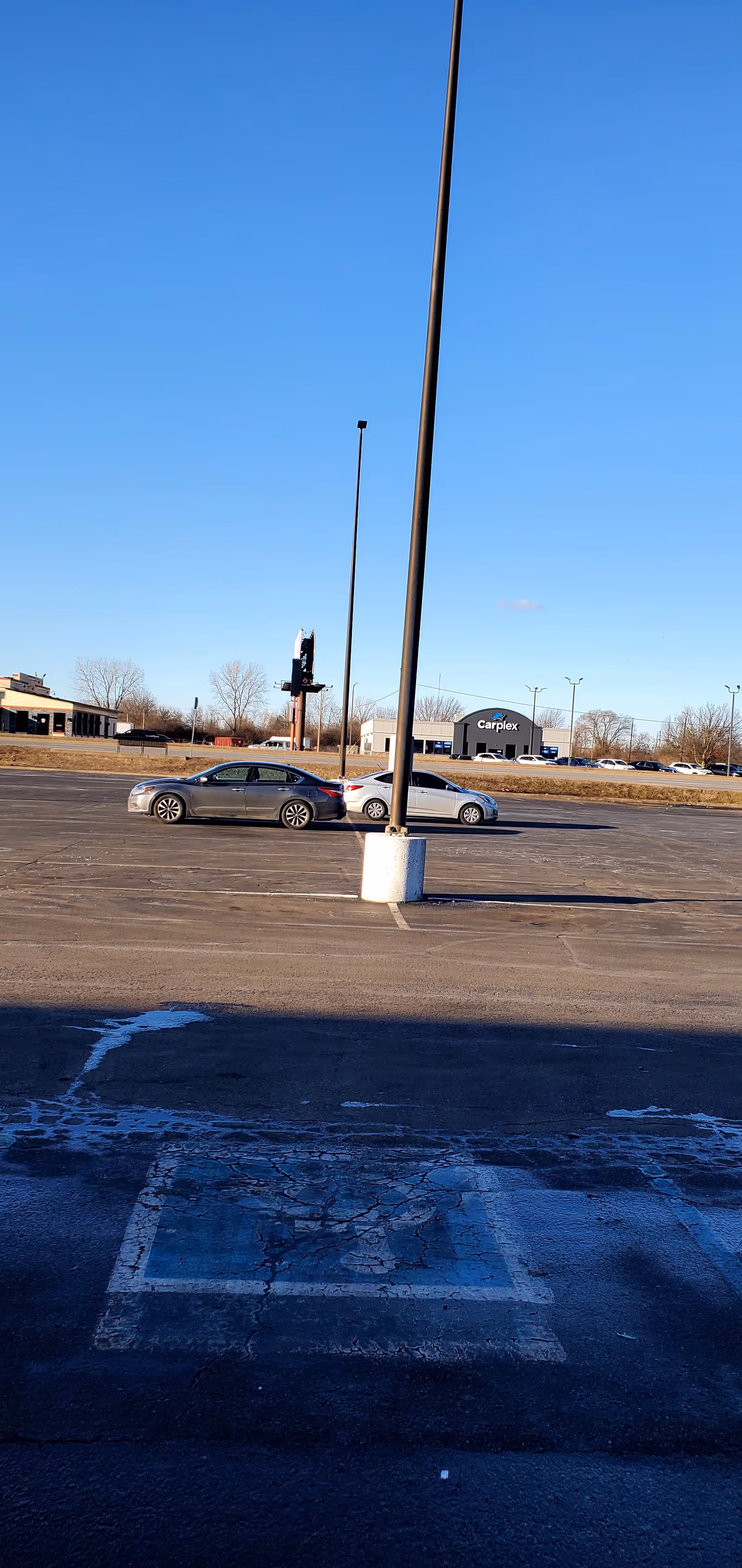 Outdoor parking lot with several cars and a clear blue sky.