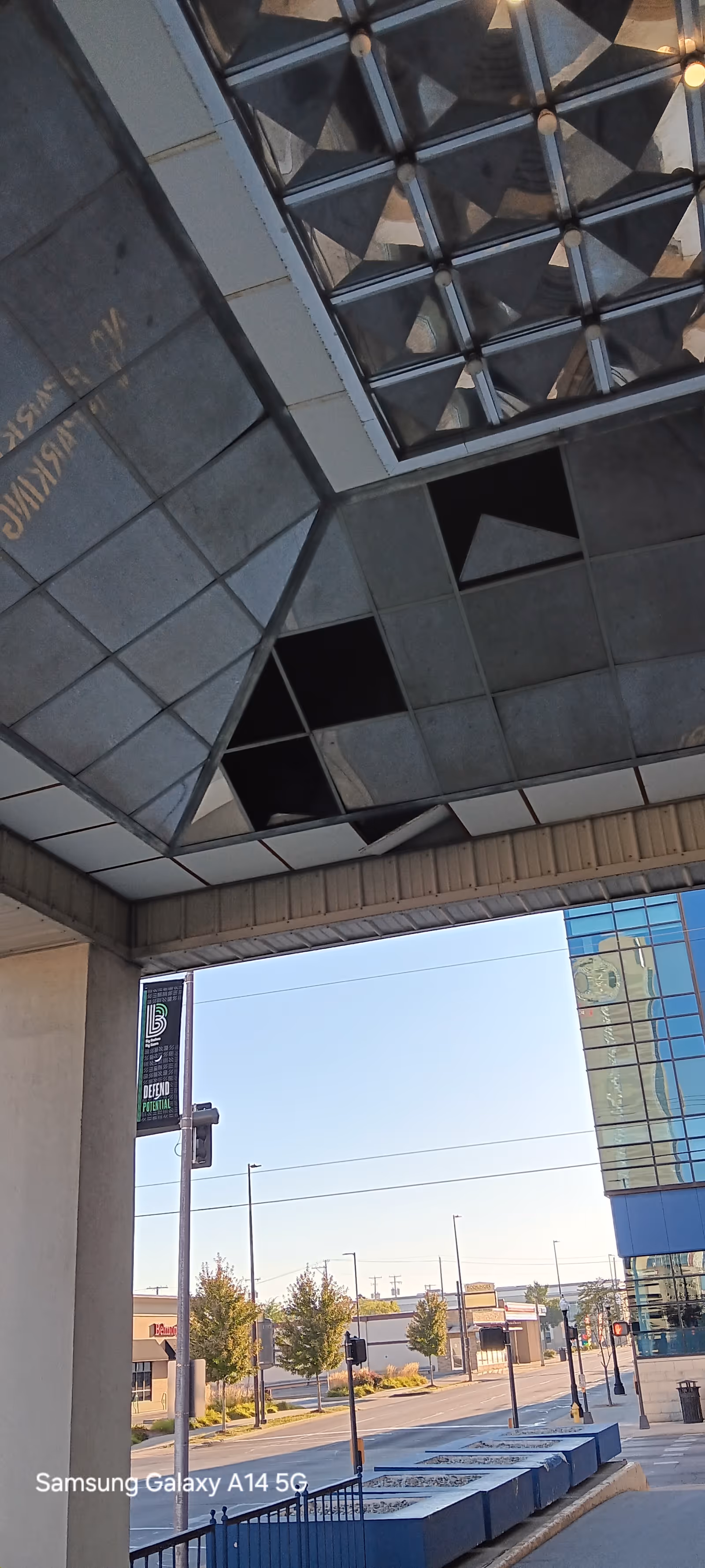 Modern building exterior with glass facade, sidewalk, and street view.