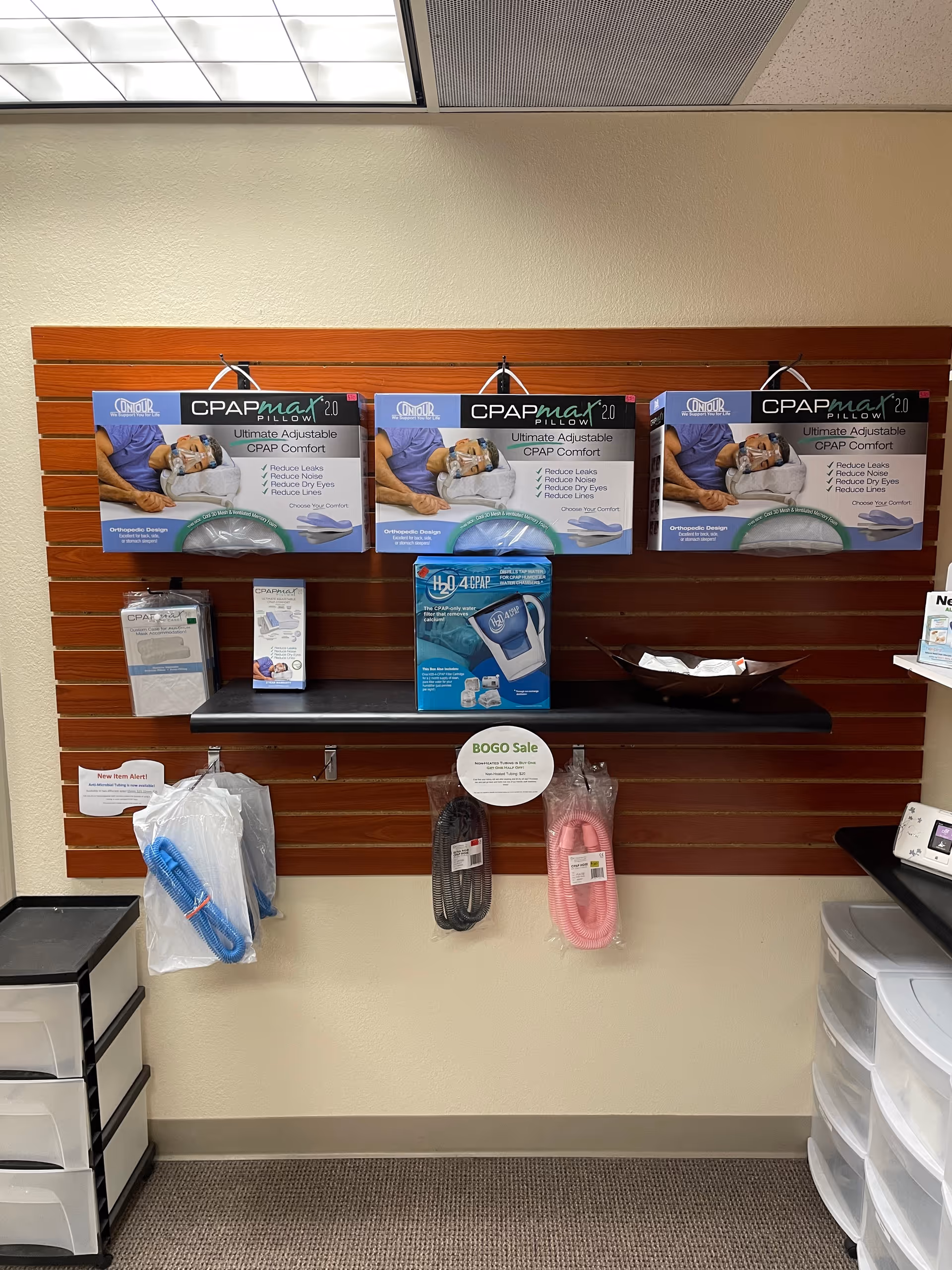 Interior wall display of CPAP pillows and hoses on a wooden slat backdrop.