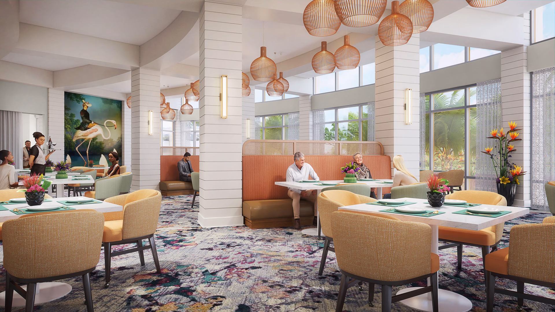 A bright and spacious dining room in a senior living facility with large windows letting in natural light. The room features multiple tables with yellow and green cushioned chairs, green placemats, and floral centerpieces. There are several pendant lights hanging from the ceiling and a colorful patterned carpet. People are seated at some tables, and a server is attending to guests. A large painting of a woman riding a flamingo is visible on one wall.