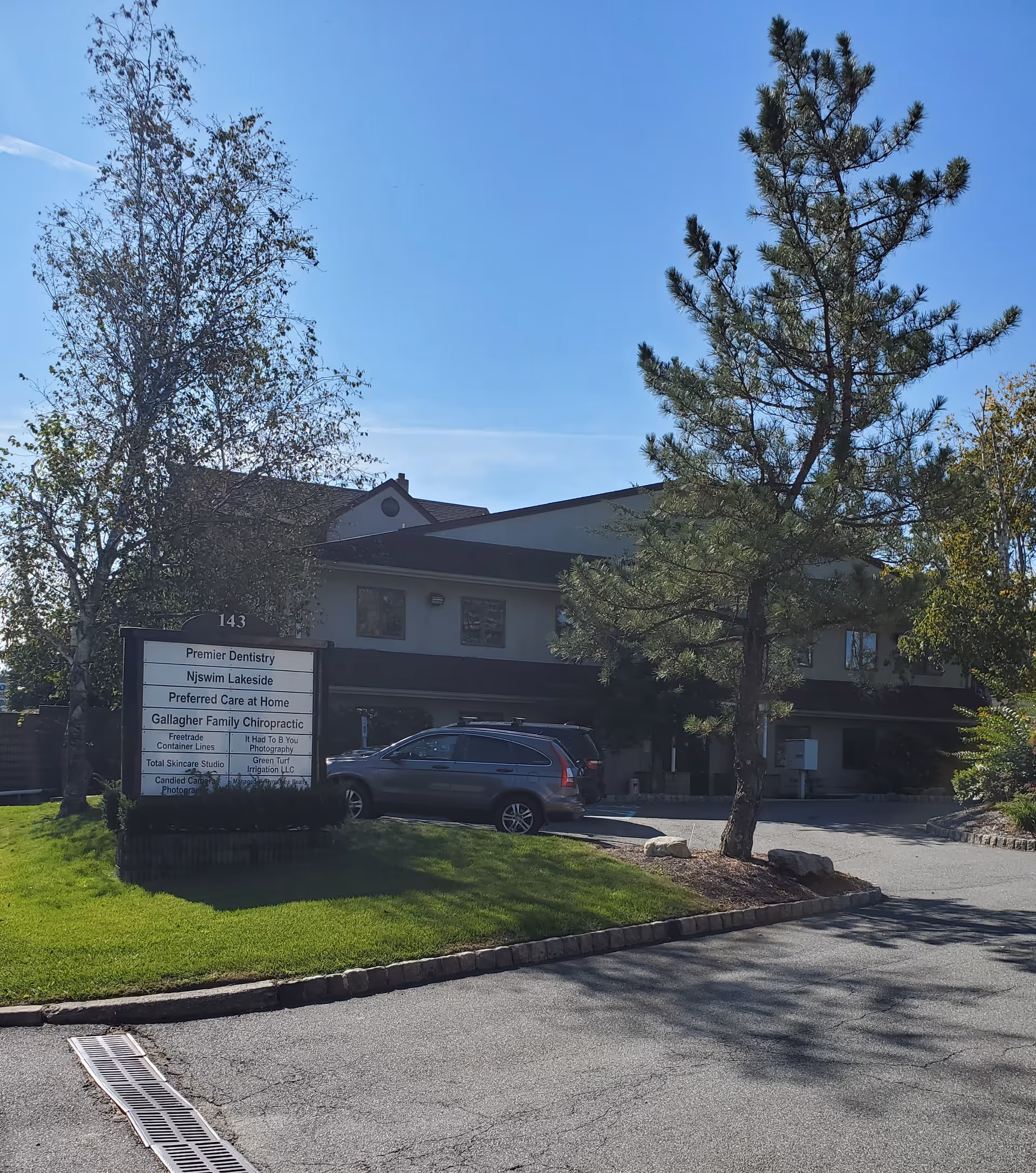 Exterior view of Preferred Care at Home building with sign, trees, and parked cars.
