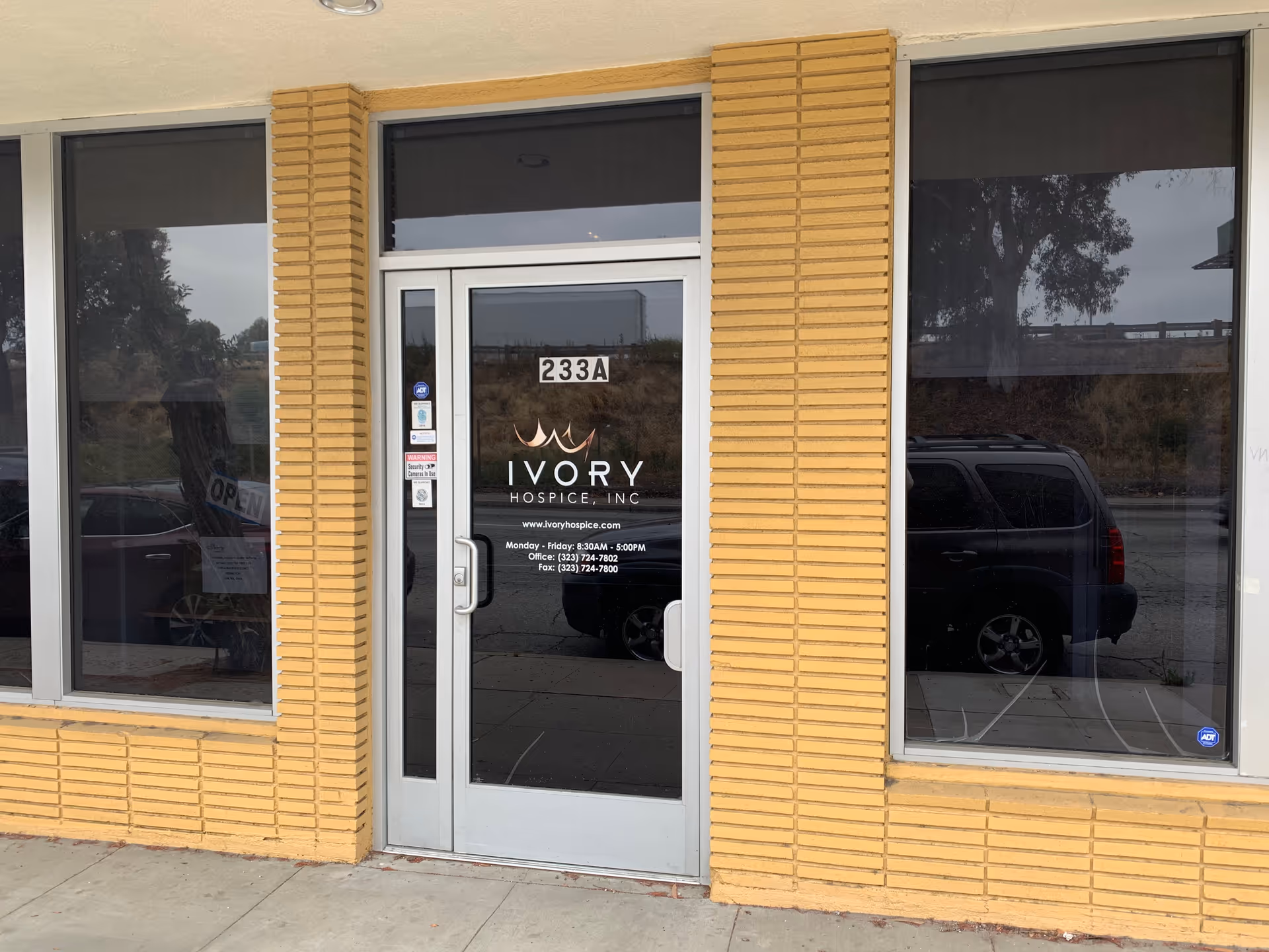 Entrance of Ivory Hospice & Palliative Care with glass door and brick exterior.