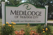 Sign for Medilodge of Traverse City with flowers in front.