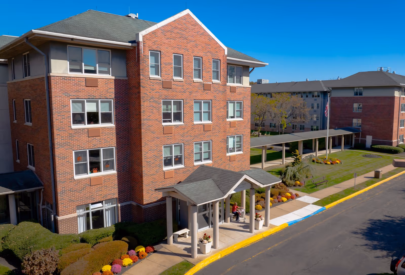 Exterior view of Siena Village at Wayne: brick senior living facility with a covered entrance.