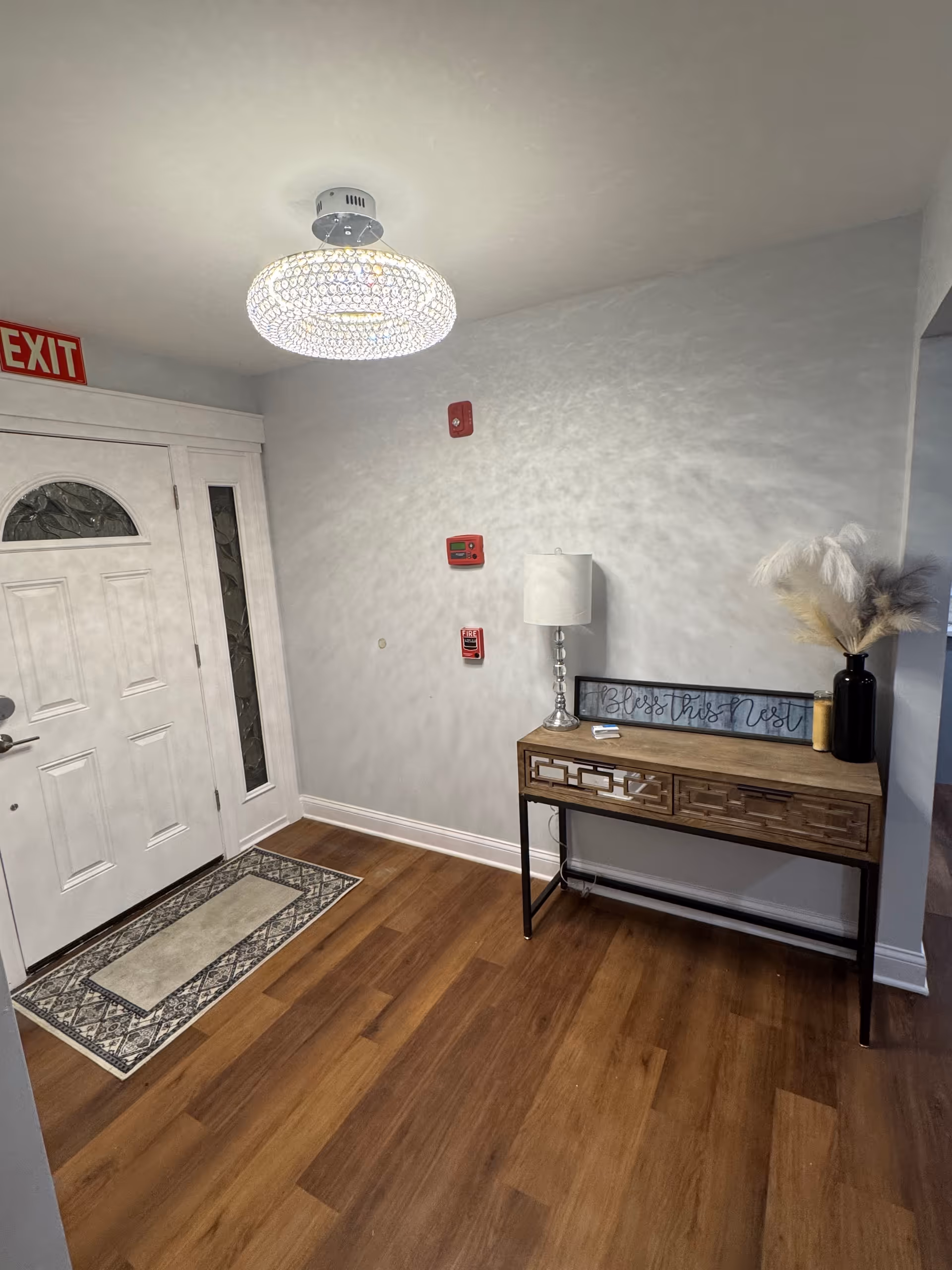 Entryway with front door, rug, console table, lamp, and decorative vase.