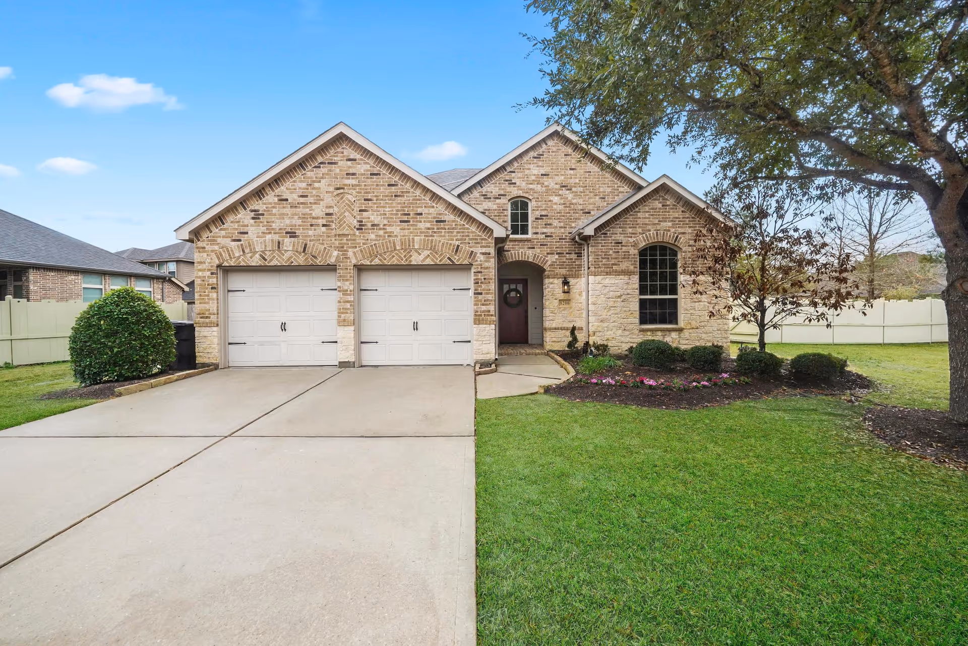 Brick-faced, single-story home with two-car garage and manicured front lawn.
