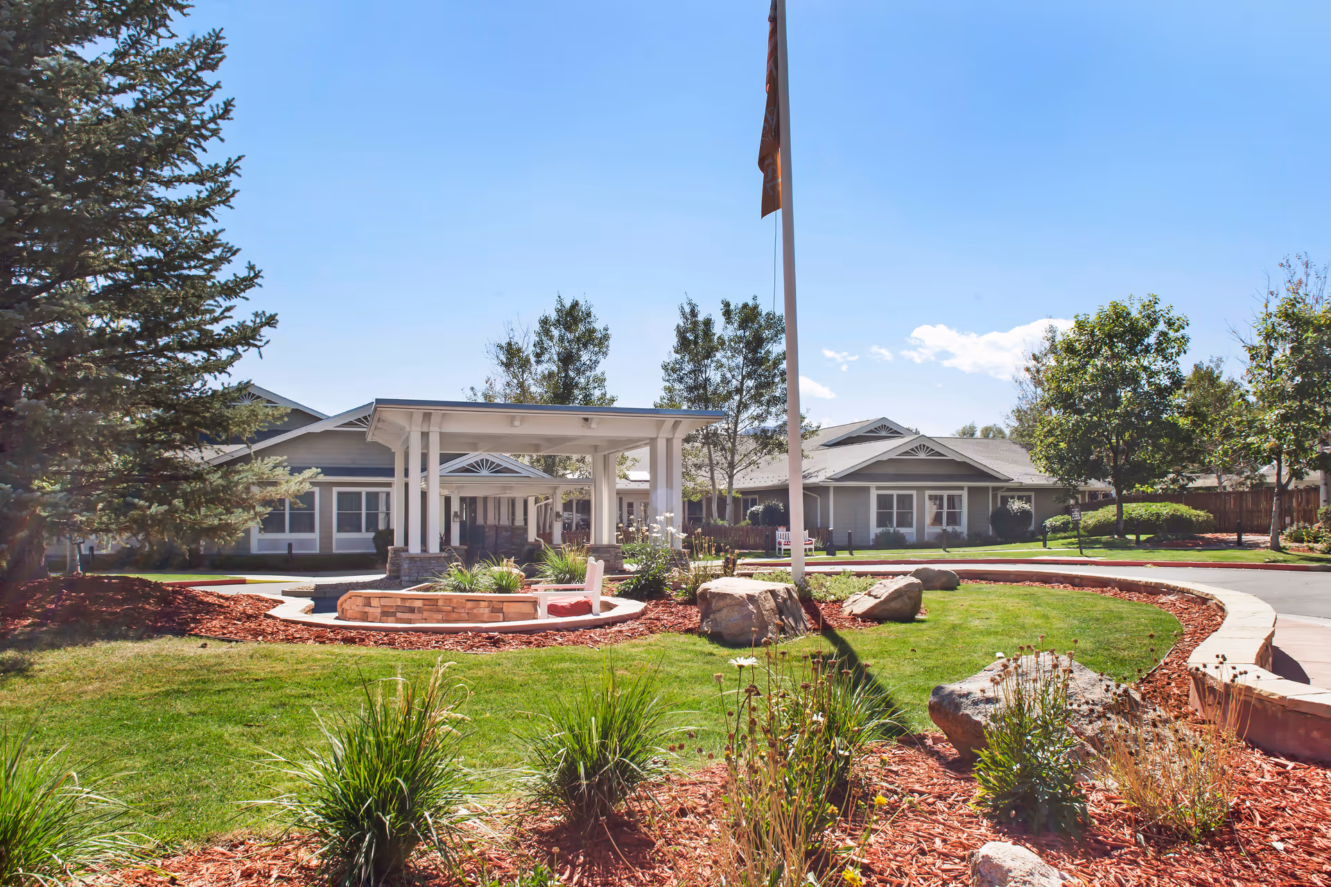 Sunrise of Boulder facility front exterior with entrance canopy, landscaping, and a flagpole.