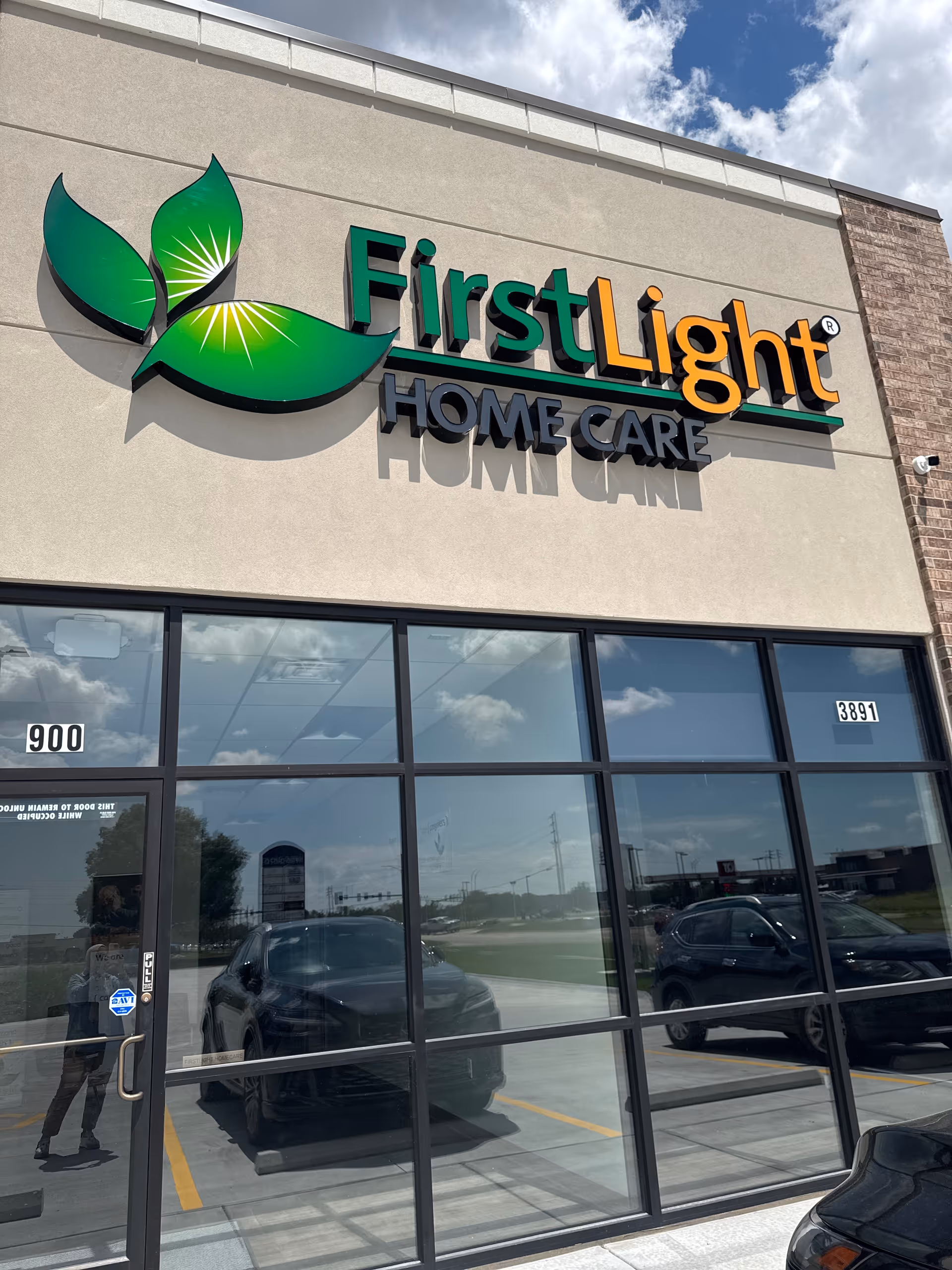Exterior of FirstLight Home Care storefront with large logo sign and glass doors.