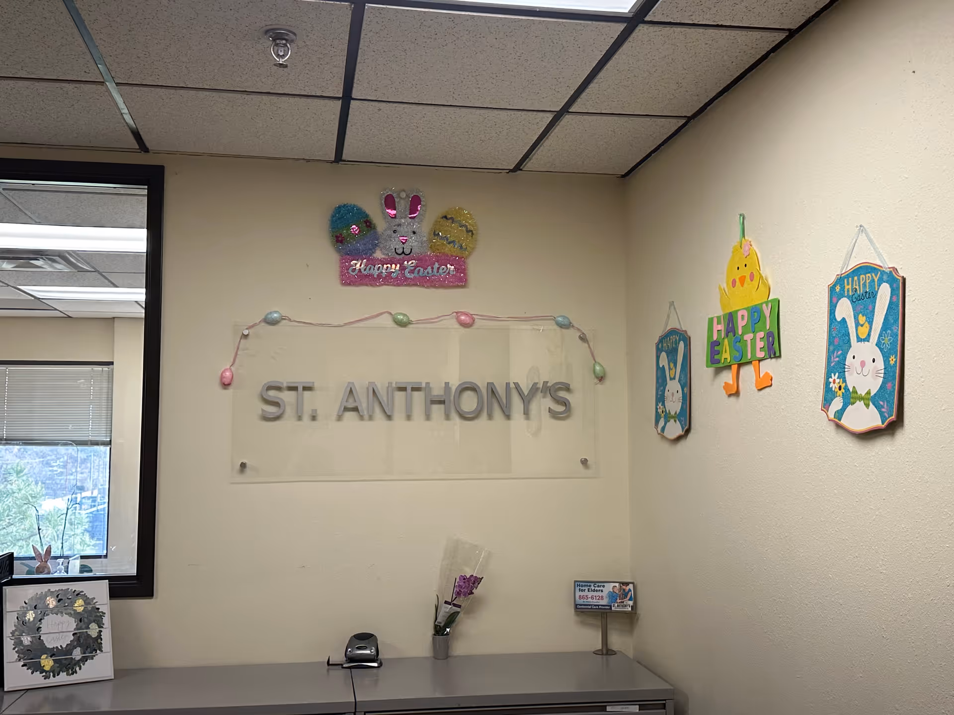Interior wall with St. Anthony's sign, Easter decorations, and a reception counter by a window.