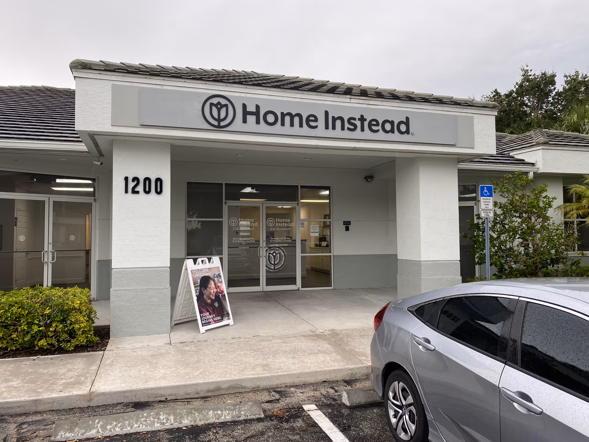 Front view of a Home Instead entrance with sign, glass doors, and a parked car.