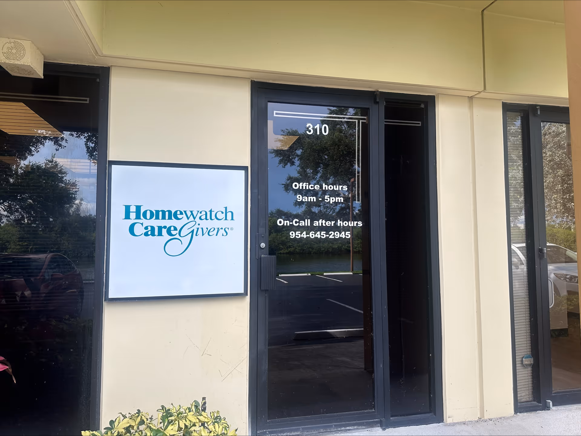 Facility entrance with Homewatch CareGivers sign and glass door displaying hours.