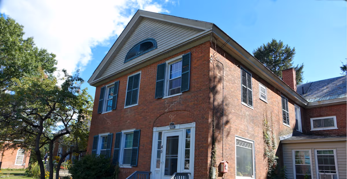 Exterior view of a brick senior living facility with a front entrance and trees.