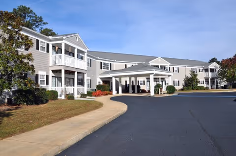 Exterior view of Brookdale Newnan with a two-story building, curved driveway, and covered entrance.