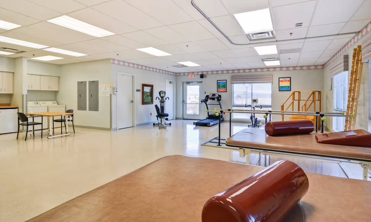 Spacious rehabilitation gym at Donahoe Manor with equipment and therapy bars.