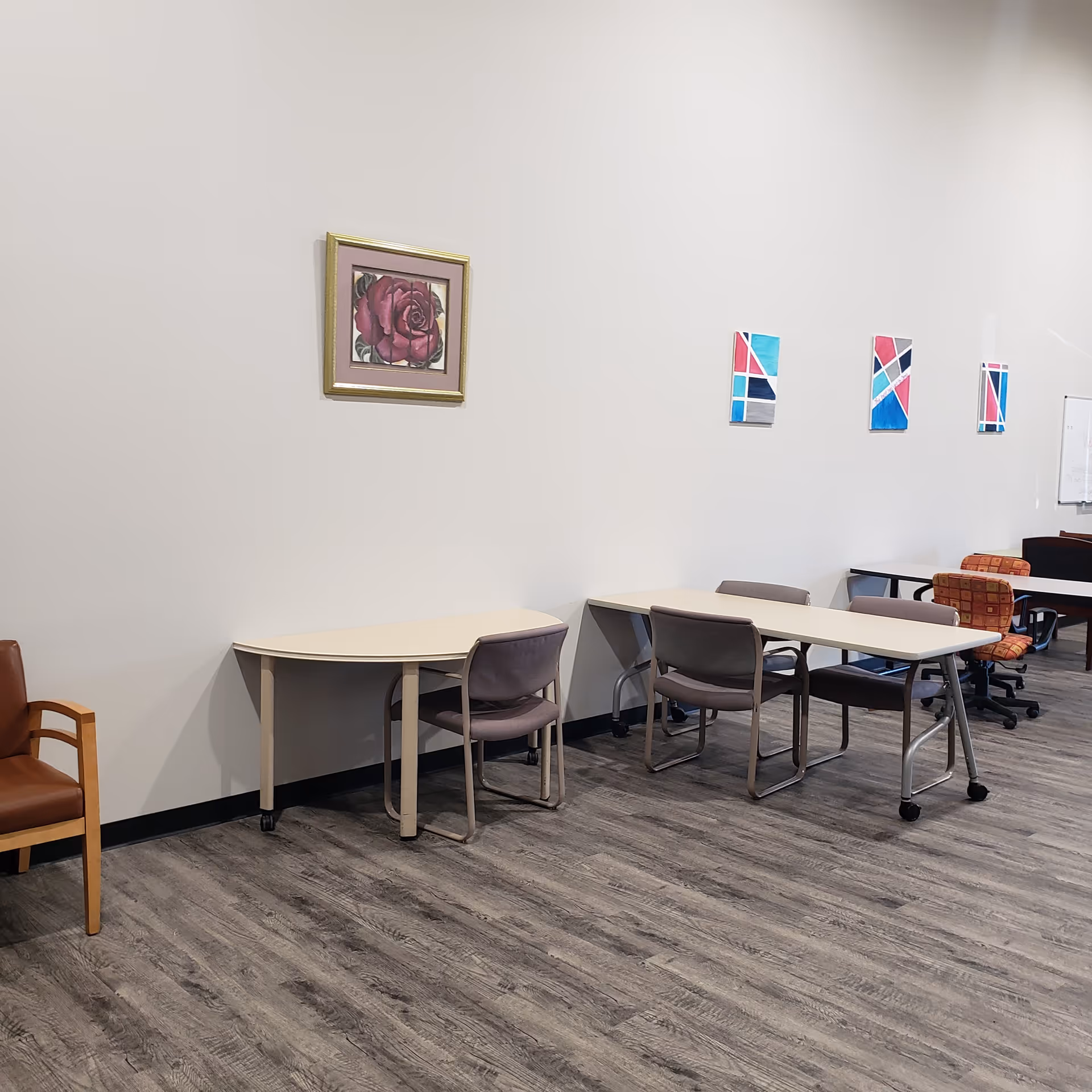 An empty dining area with several tables, chairs, and wall artwork.