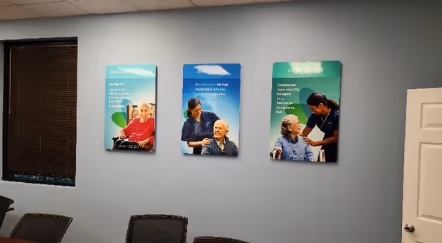 Waiting area with a light-gray wall, three mounted posters, and surrounding chairs.