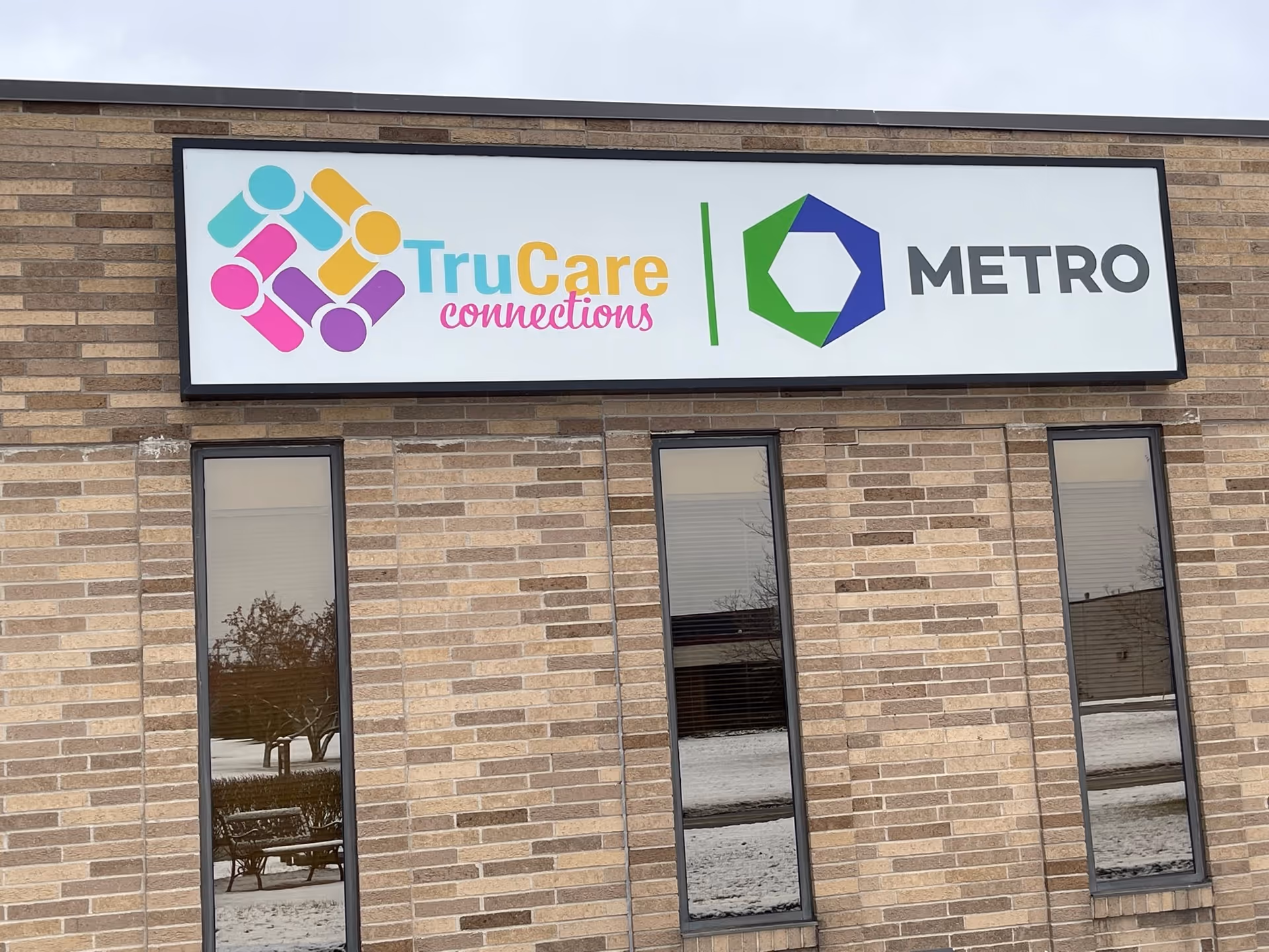 Brick building exterior with a large TruCare Connections sign and Metro logo on the front.